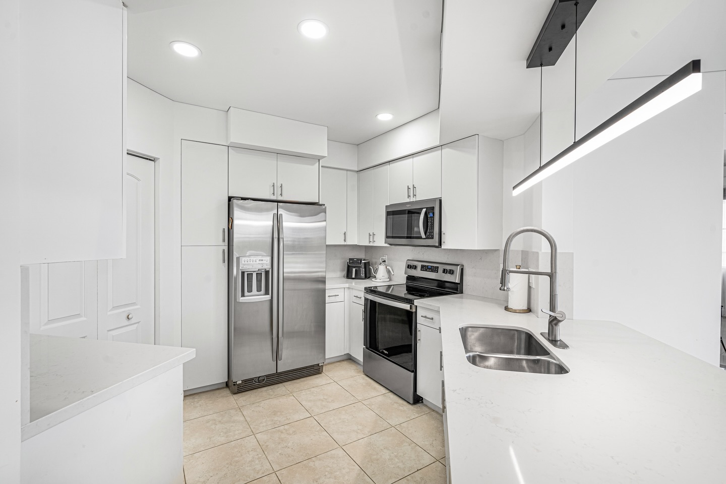 Modern white kitchen with stainless appliances and quartz counters