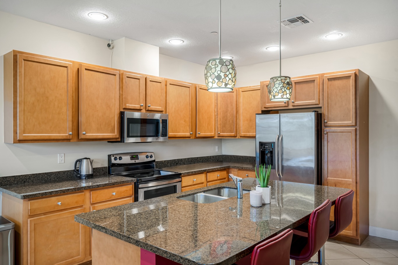 Bright Florida condo kitchen with granite counters and warm wood cabinets